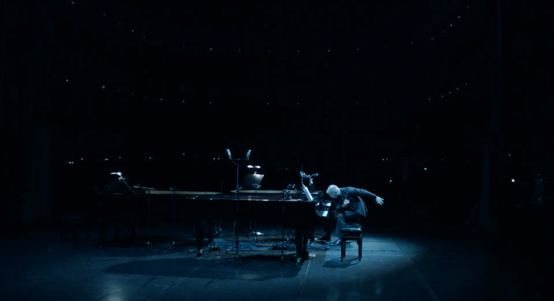 Matthew Mayer taking a bow at a grand piano on a dark concert-hall stage beneath a starlit ceiling, Croatia