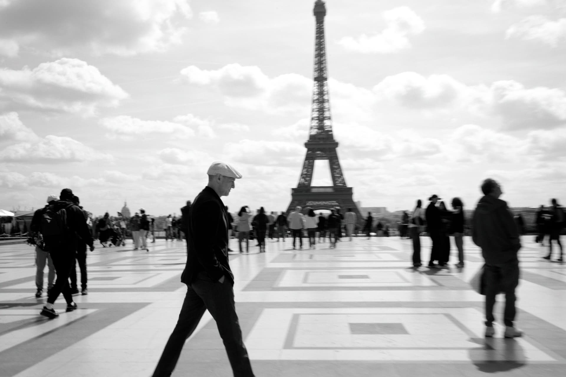 Matthew Mayer walking across the Trocadéro esplanade in Paris, with the Eiffel Tower rising behind him