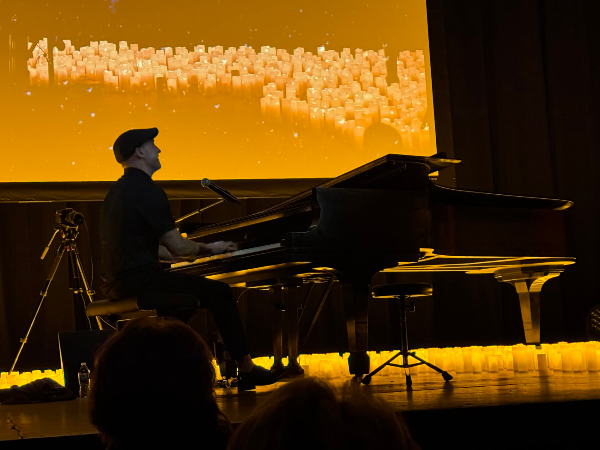 Matthew Mayer performing live on a grand piano at a candlelit concert at the Orpheum Theater in Sioux Falls, South Dakota, beneath a golden projection of candles